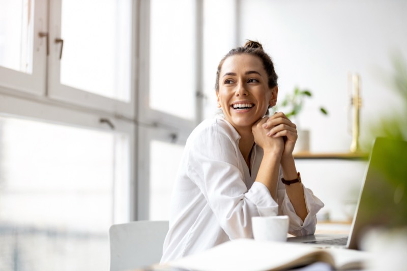 A woman smiling by a bright window